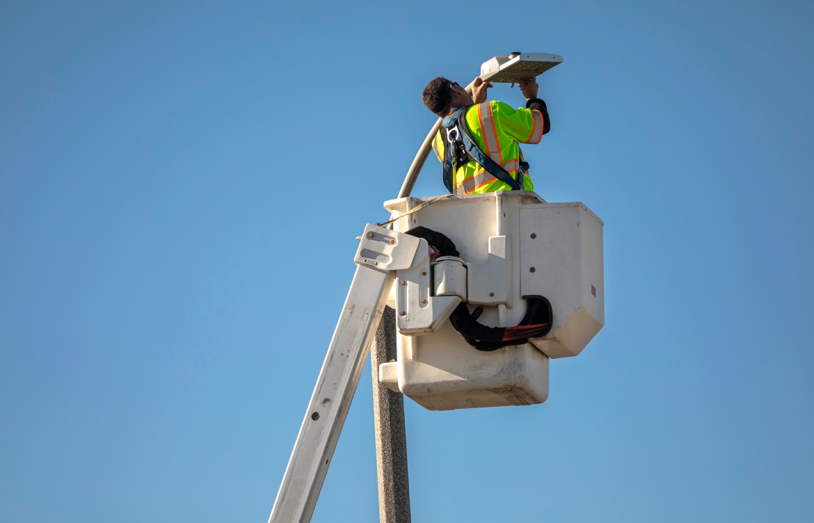 Utility worker at top of street light pole.