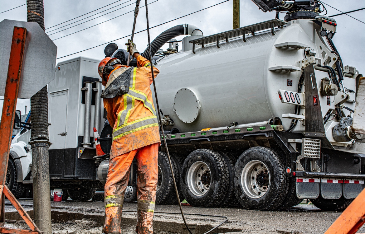 Utility worker holding Hydro vac machine.