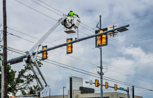 Utility worker using bucket truck to fix traffic lights issues.