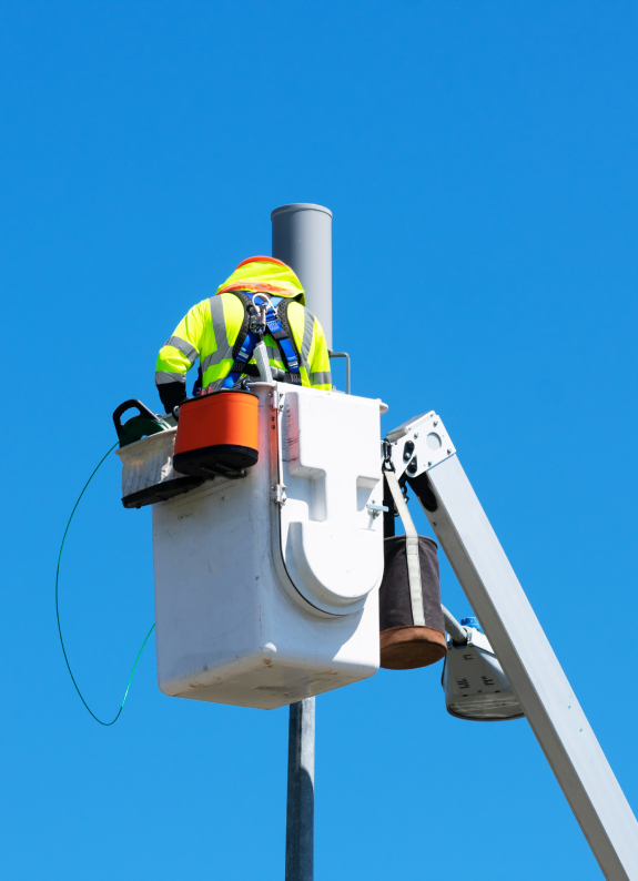 Utility worker using bucket truck to fix street pole issues.